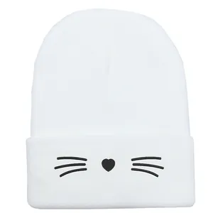 Berretto in maglia bianca con ricamo di gatto carino e naso a cuore su sfondo bianco