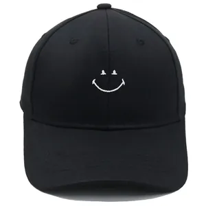 Close-up of white embroidered smiley face on a black cotton baseball cap detail