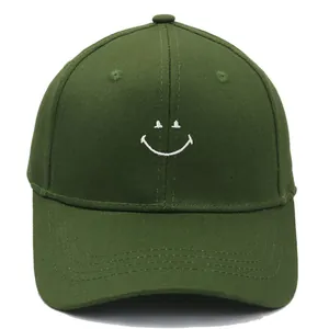 Close-up of olive green baseball cap with white smiley face embroidery and curved brim