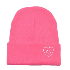 Bonnet en maille rose vif avec broderie smiley en forme de cœur blanc et revers