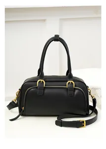 Detailed close-up of matte black leather bag with premium gold hardware and dual handles