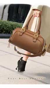 Brown leather bowling handbag detail with gold hardware and removable shoulder strap