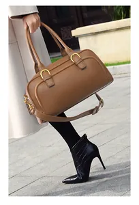 Detailed close-up of brown pebbled leather texture and gold buckle hardware on handbag