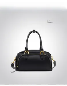 Detail of black bowling handbag with gold hardware and dual zippers in matte leather