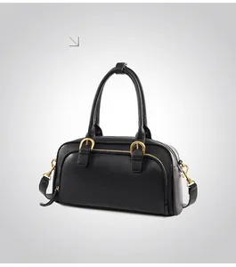 Close-up of black retro bowling handbag showing golden zipper and leather texture