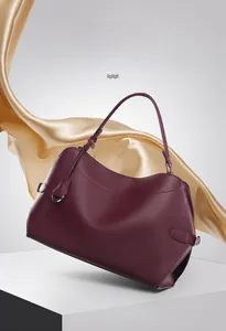 Close-up of elegant wine red handbag featuring curved top edge and metal ring detail