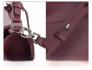 Detail of adjustable and detachable shoulder strap with silver hardware on burgundy bag