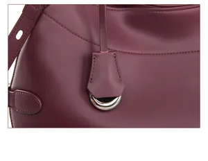 Detail of burgundy leather shoulder bag with detachable silver metal pendant charm