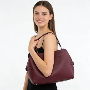 Burgundy oversized faux leather tote bag with shoulder strap shown on a smiling model