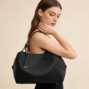 Detailed close-up of a black leather shoulder bag featuring a half-moon metal ring accent