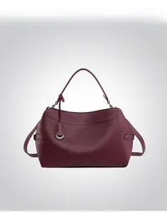 Front view of a burgundy leather handbag with grain texture and metallic charm detail