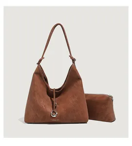 Detail van bruine matte tote en bijpassende pouch met geknoopte handgreep en metalen ring