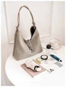 Detail van grijze leren hobo tas met slanke bandjes en metalen ring hanger detail