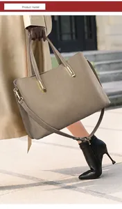 Detailed macro view of litchi grain leather texture and gold metal hardware on tote bag