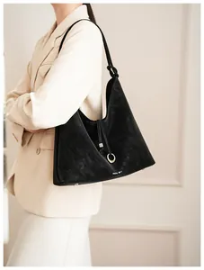 Detailopname van zwarte suède hobo tas met trekkoord detail en MUSE BAG logo opdruk