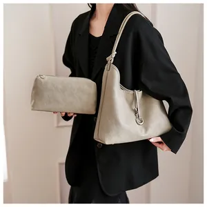 Detail van minimalistische beige hobo-tas met bijpassende ritszak en metalen ringdecoratie