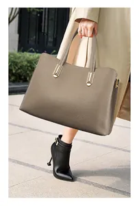 Detail of grey leather tote bag with lychee texture and golden metal buckle details