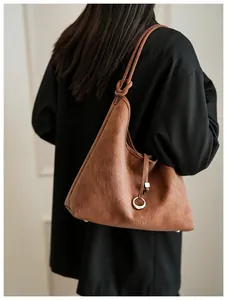 Detail van donkerbruine matte leren shopper met een gouden ringbedel en logo-reliëf