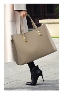 Detailed macro view of litchi pattern leather and gold metal buckle on tote bag