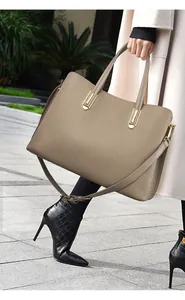 Macro shot of khaki lychee grain leather tote bag with gold hardware and side strap
