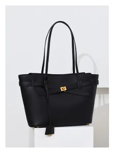 Close-up of black matte faux leather tote bag with gold metal twist lock and strap detail
