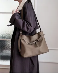 Close-up of pebble leather texture and metallic buckle on a stylish taupe tote bag