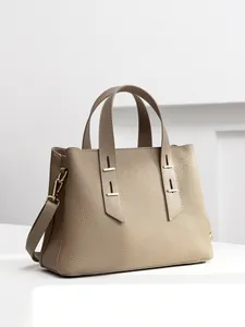 Elegant earth-tone Togo leather tote bag with pebble texture and gold hardware on white steps