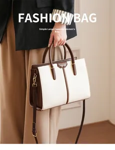 Detail of contrast color tote bag with gold logo and comfortable leather handles