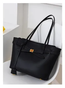 Close-up of black leather tote bag featuring a gold Kelly-style turn-lock and studs