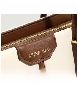 Detailed macro view of Muse Bag logo with gold hardware and premium stitching texture