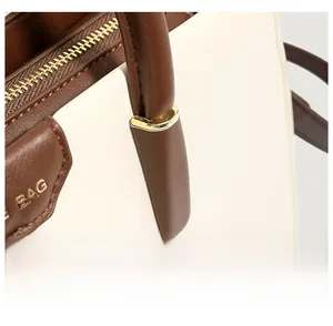 Detailed close-up of two-tone leather handbag with golden buckle and fine stitching