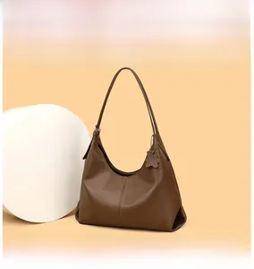 Detail of brown litchi pattern leather tote bag with cute bear charm and shoulder strap