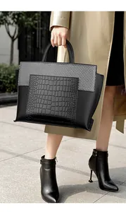 Business style large black tote bag with crocodile texture carried by a model outdoors