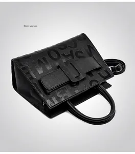 Detailed close-up of black lychee leather tote bag with embossed letters and strap