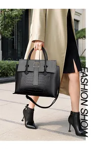 Detailed view of crocodile pattern texture and T-strap buckle on a large black tote bag
