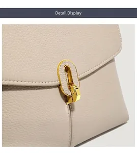 Macro detail of golden oval twist lock and lychee texture leather on beige handbag