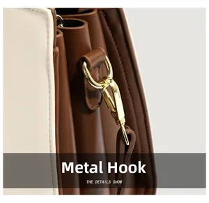 Detailed macro view of golden metal hardware hook on color-block leather handbag strap