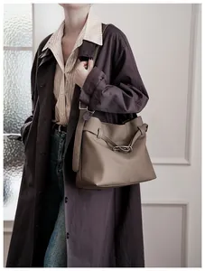 Detail of coffee brown tote bag with pebbled leather texture and metal buckle detail