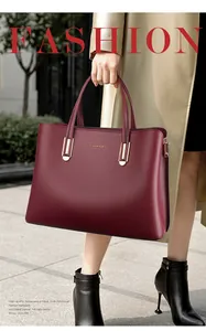 Detail of burgundy textured leather tote bag with gold hardware and brand logo