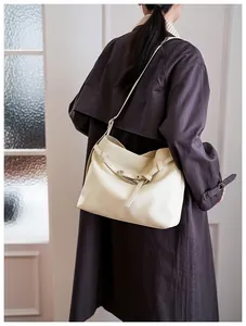 Close-up of cream leather tote bag featuring litchi grain texture and adjustable buckle