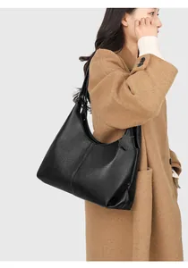 Close-up of black lychee grain leather tote bag worn with a stylish camel wool coat