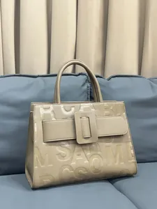 Detail of beige lychee texture leather tote bag with letter print on a sofa
