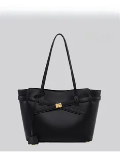Detail of minimalist black tote bag with gold buckle fastener and long shoulder strap