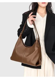 Detail of large brown pebble leather tote bag featuring long shoulder straps and soft texture