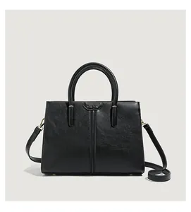 Detail of matte black leather handbag with round handle, shoulder strap and NICE BAG logo