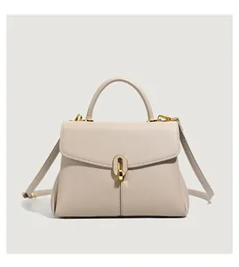 Close-up of beige lychee grain leather handbag featuring a golden oval metal buckle lock