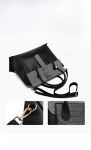 Detail of black crocodile texture leather bag with golden hooks and detachable strap