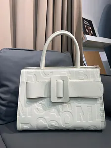 Detailed view of the embossed leather texture and large buckle on the cream tote bag