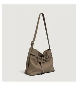 Detail view of khaki pebbled leather tote bag with decorative metal buckle and strap