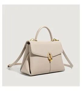 Close-up of beige lychee texture leather handbag with elegant gold metal twist lock